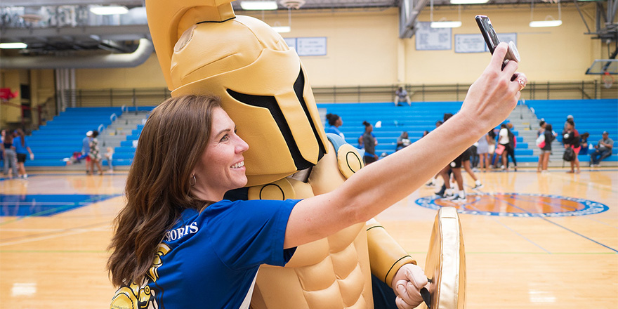 woman taking a selfie with the trojan mascot