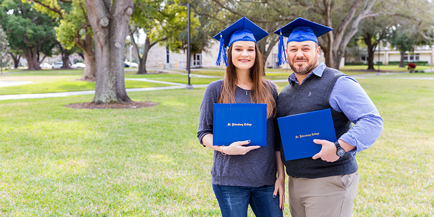 female and male graduates standing in a park